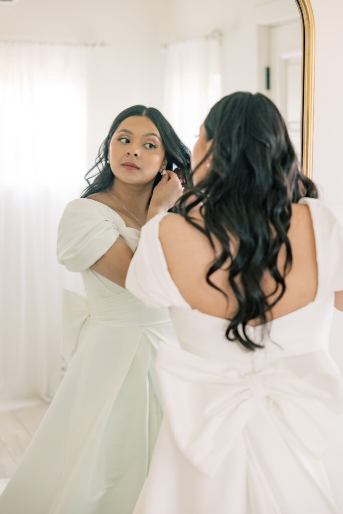 Bride admiring herself while adjusting her ear ring. Tuscan Rose Ranch