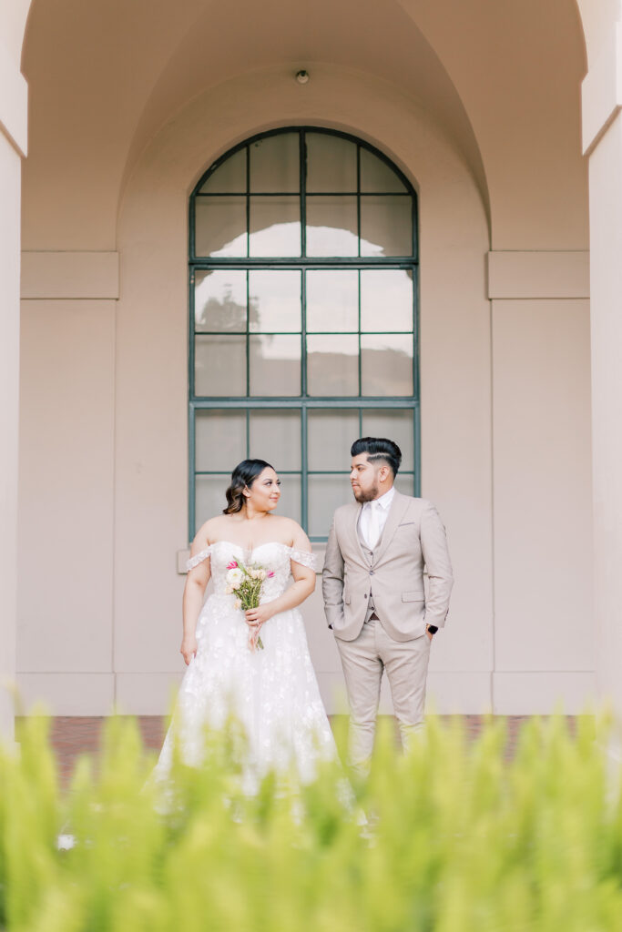 Bride and groom standing under arch looking at each other