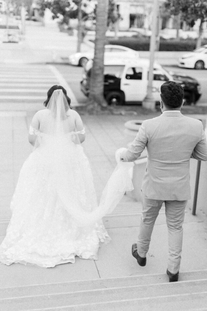 bride and groom walking down stairs. groom is holding her train.