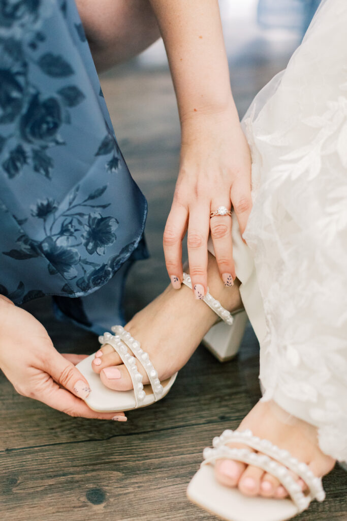 maid of honor putting bride's shoe on