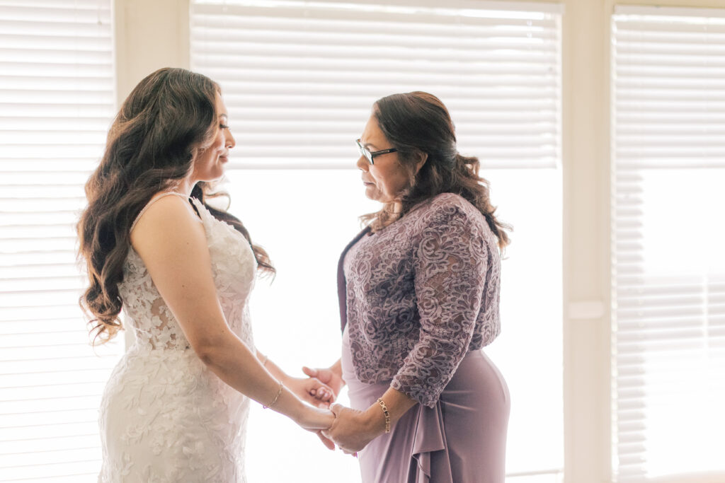 Bride and mother holding hands in prayer