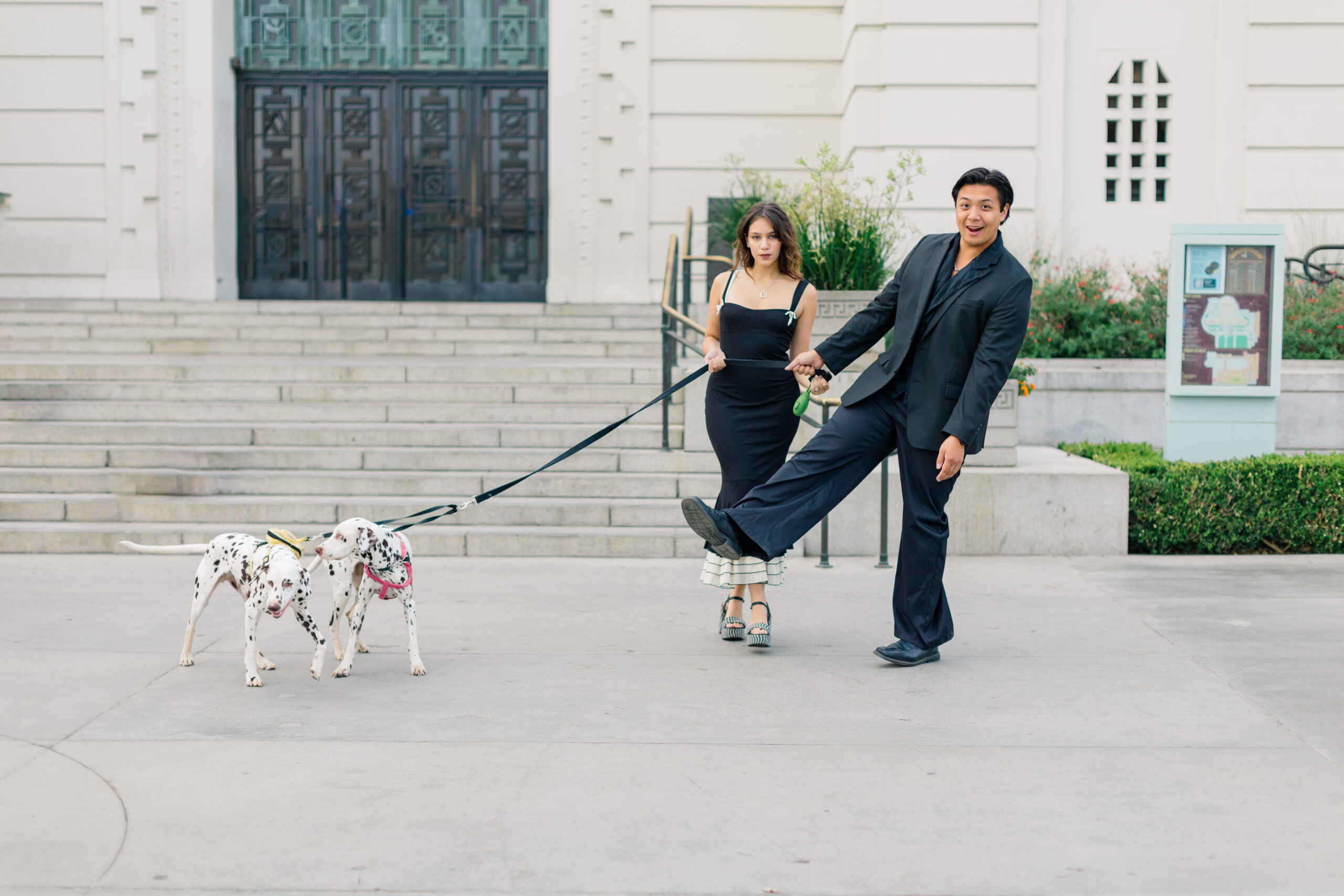 Couple standing in front of the Griffith Observatory holding on to a dalmatian