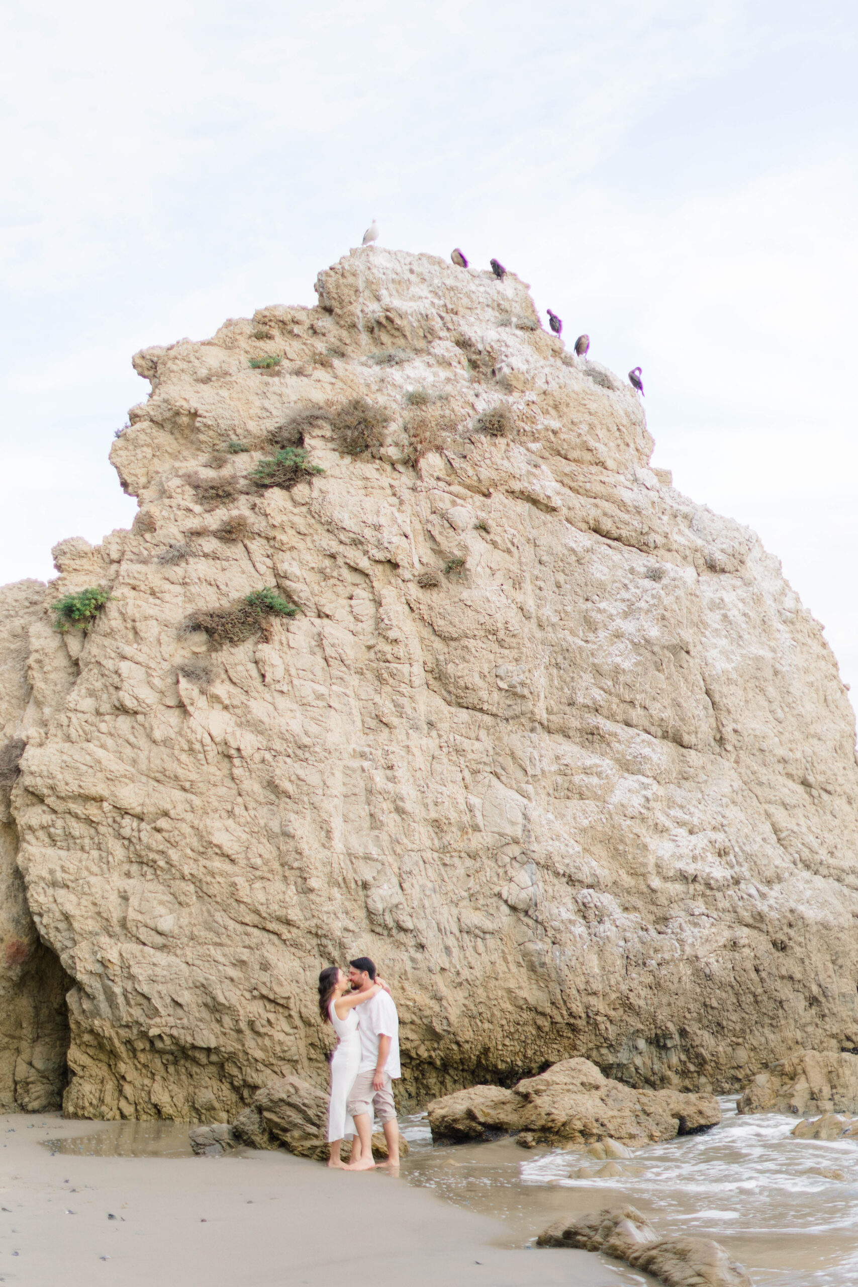 Couple standing in front of a rock formation at El Matador State Beach